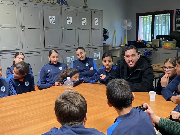 Le footballeur Rayan Cherki est attablé et discute avec les enfants de l'AS Buers
